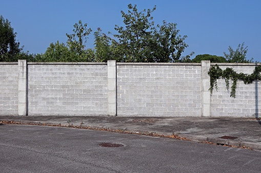 Cinder block wall with a sidewalk and a street in front. Suburban background for copy space