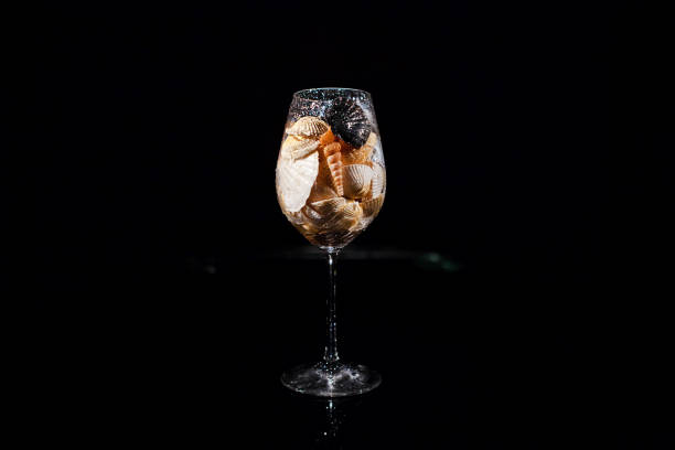 Sparkling wineglass with shells stands on black table