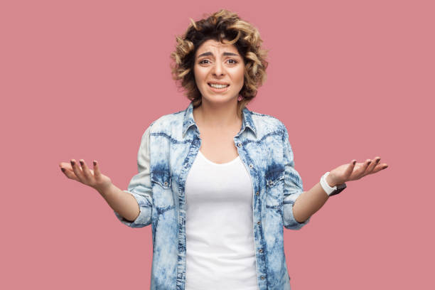 what? portrait of confused or shocked young woman with curly hairstyle in casual blue shirt standing with raised arms and looking at camera worried. - rudeness manager emotional stress asian ethnicity imagens e fotografias de stock