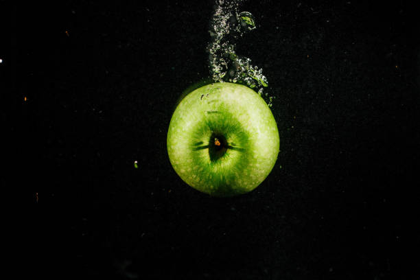 istock Green apple splashes water falling on black background 1160763507