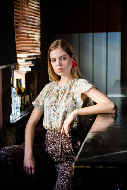 istock beautiful blonde model sits behind an empty bar counter and looks away 1160764146