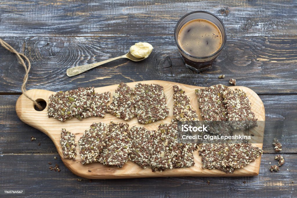 Köstliche gesunde Glutenfreie Knacker, ketogen, aus Chia-Samen, Lein, Sesam und gemahlenen Kürbiskernen und Keto-Kaffee im Glas mit Löffel Butter - Lizenzfrei Bildhintergrund Stock-Foto