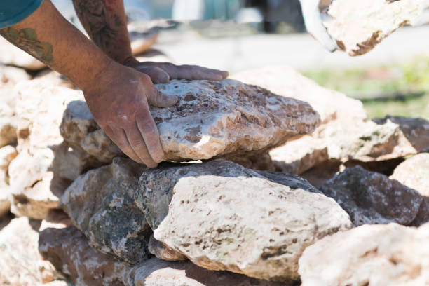 worker's hands put the stone on the wall - muretto a secco - construction of a low wall - old traditional Apulian architectural art