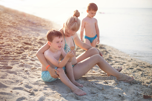 Young woman and her two little sons enjoying their beach holiday.