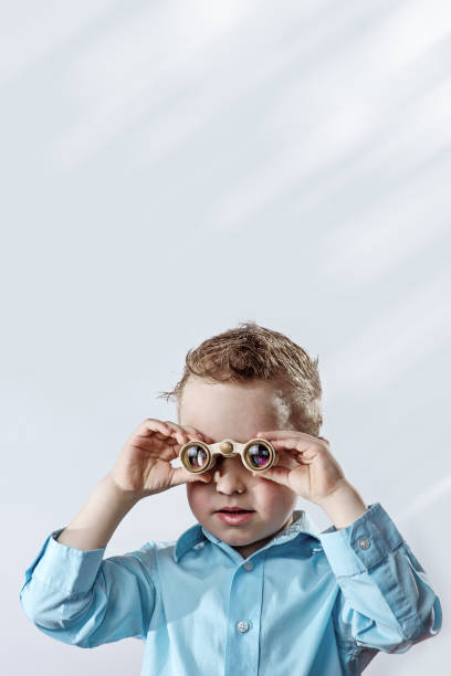 istock boy in a light shirt looking through binoculars on a light background 1160767160