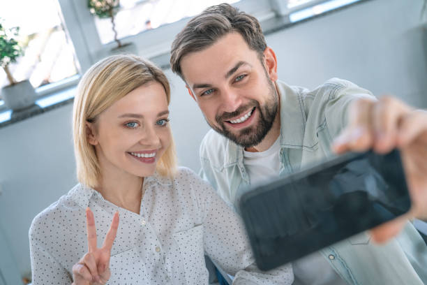 istock Smiling couple taking a selfie using mobile phone sitting at cafe 1160770296
