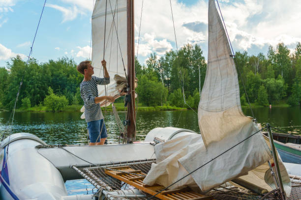 istock young sailor raises sail on a small sailing catamaran 1160770688