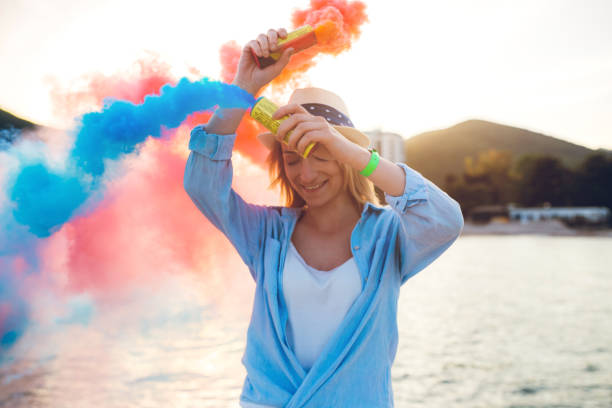 Young caucasian beautiful woman having fun with smoke bomb on the beach in Budva.