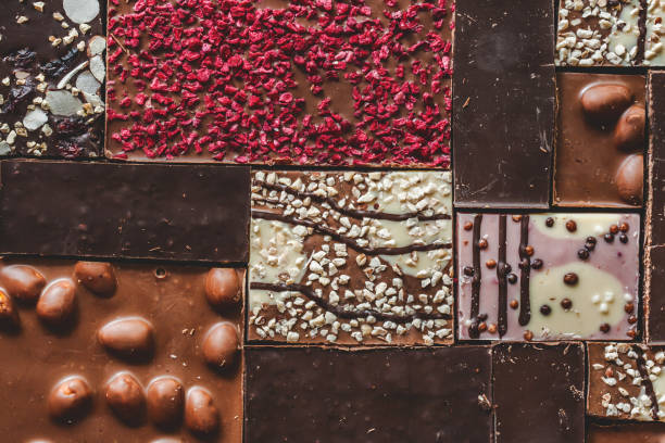 ミルク、ダークとホワイトチョコレートバーのピースと背景。ヘーゼルナッツ、ピーナッツ、ドライラズベリー、レーズンのチョコレートパズル - chocolate chocolate candy dark chocolate directly above ストックフォトと画像