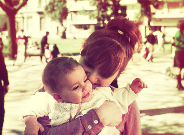 Mother with baby girl hugging at the park stock photo