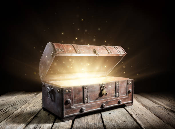 宝箱 - 暗闇の中で輝く魔法のライ トで古代のトランクを開きます - 骨董品 ストックフォトと画像