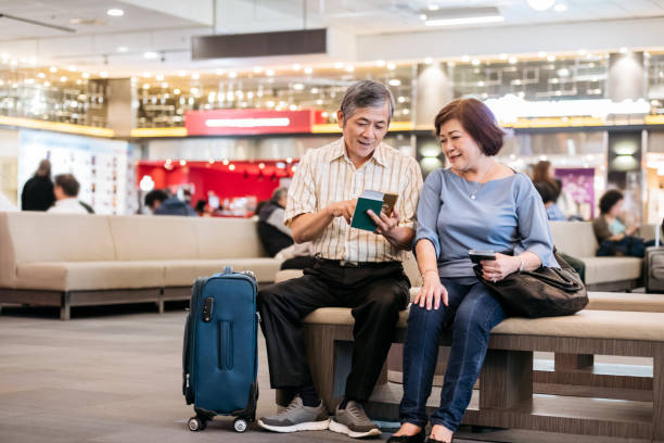 istock Senior couple using mobile phone in airport lounge 1160778482