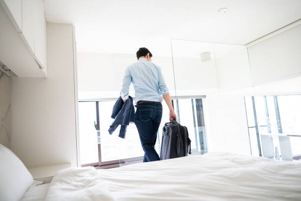 istock Rear view of man leaving hotel room with suitcase 1160779251