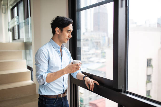 niedosłyszący mężczyzna pijący poranną kawę w pobliżu okna - window taipei built structure taiwan zdjęcia i obrazy z banku zdjęć