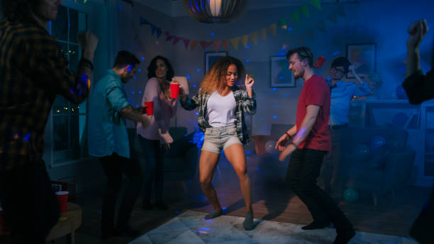 auf der college house party: sexy paar tanzt mit diversen gruppe von freunden spaß um sie herum. jungen und mädchen clubbing im wohnzimmer. disco neon strobe lichter beleuchtung raum. - music women disco joy stock-fotos und bilder