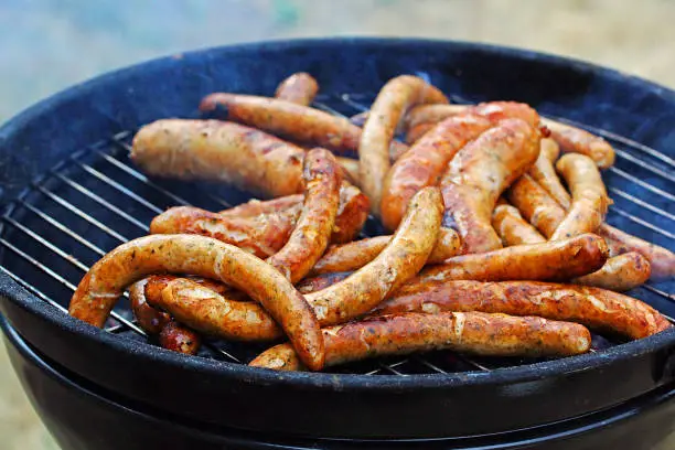 Photo of grill sausages and wieners on the grill in the smoke