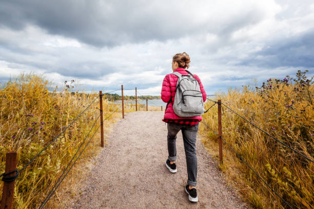 chica viajera con una mochila camina por la isla de suomenlinna en un hermoso día de otoño, un viaje a la naturaleza en el norte de europa, finlandia - suomenlinna fotografías e imágenes de stock