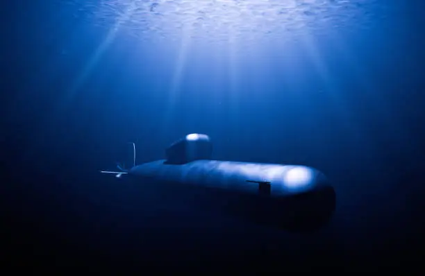 Submarine hunting in immersion while rays of light in the waves illuminate it