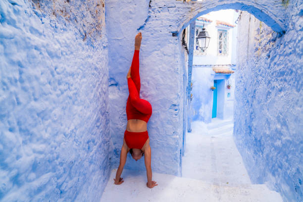 Young woman performs handstand against wall