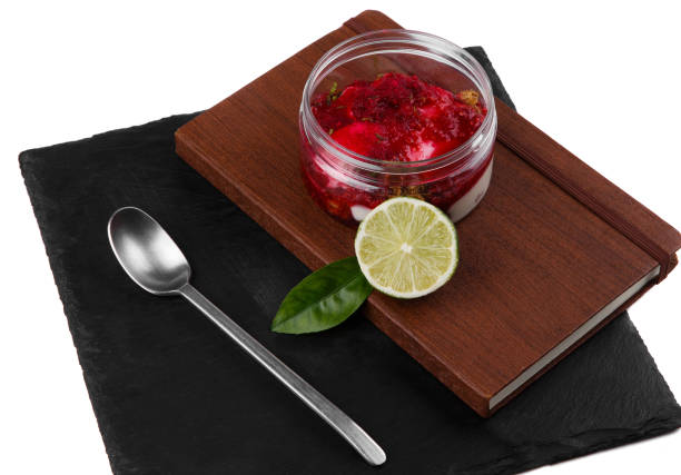 Raspberry cheesecake dessert in a jar on a black stone plate isolated on a white background