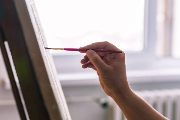 Close up of artist painting in front of window stock photo