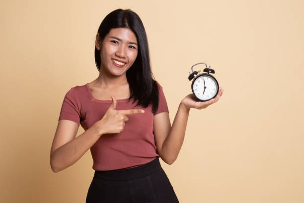 istock Young Asian woman point to a clock. 1160793371