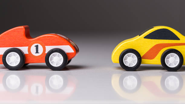istock Red and yellow tiny toy cars reflected on a white surface 1160796331