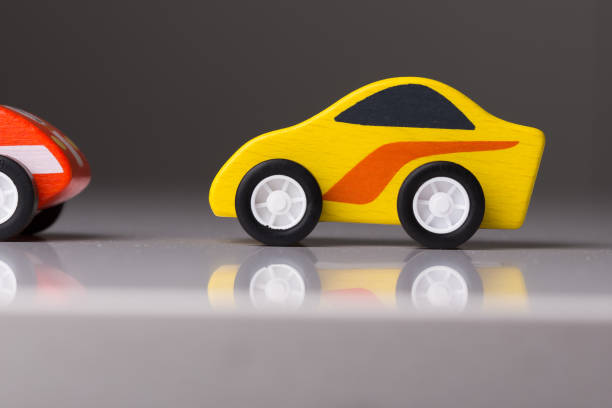 istock Yellow racing toy car on a white reflective surface 1160796462