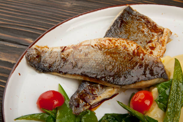 istock baked fish with vegetables on wooden background 1160796726