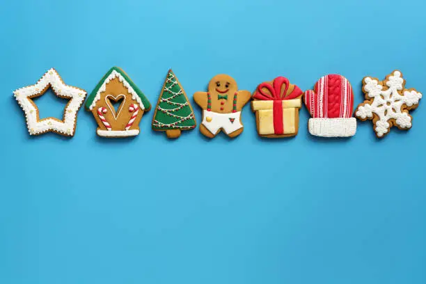 Photo of A variety of Christmas gingerbread in a row on a blue background. Top view, flat lay, copy space. The concept of the holiday.