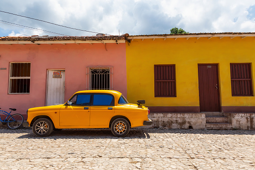 Trinidad, Cuba - June 6, 2019: View of an Old Classic American Car in the streets of a small Cuban Town during a vibrant sunny day.