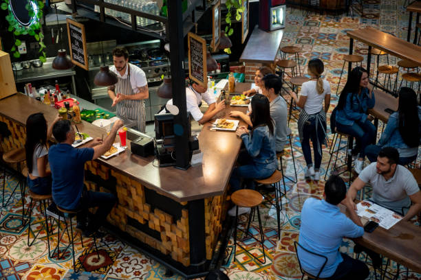 Group of Latin American customers eating at a restaurant and looking happy - food and drinks concepts