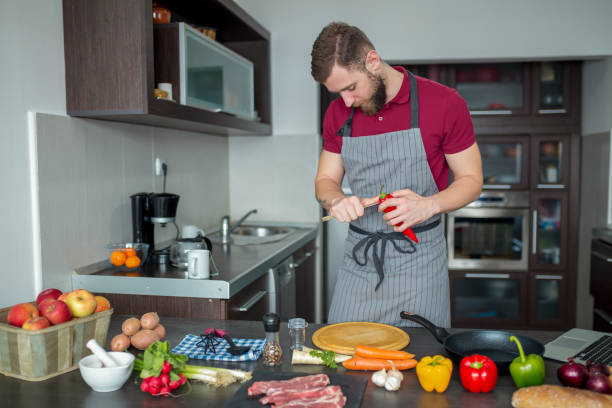 istock Man cuts fresh spring vegetables on the kitchen table, closeup. Preparing homemade food, home kitchen interior. 1160808932