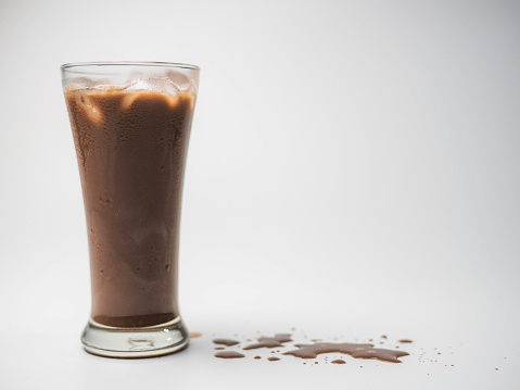 Iced chocolate or cacao in clear glass on white isolated background in side view with copy space. Concept to present bitter sweet and delicious drink.