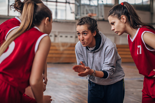 Female coach standing with basketball team on basketball court