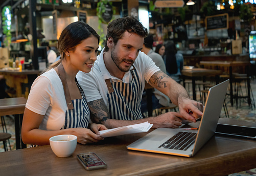 Staff working at a restaurant managing the finances using a laptop computer - small business concepts
