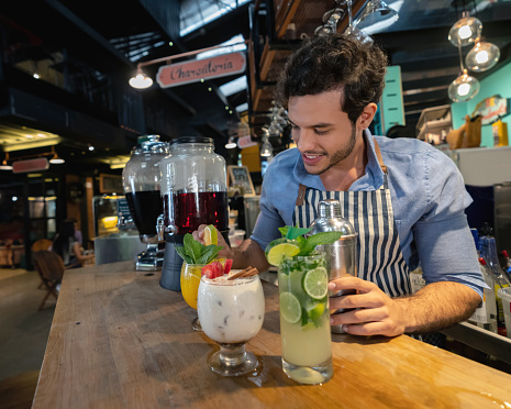 Portrait of a happy bartender making drinks at the bar and smiling - food and drinks concepts
