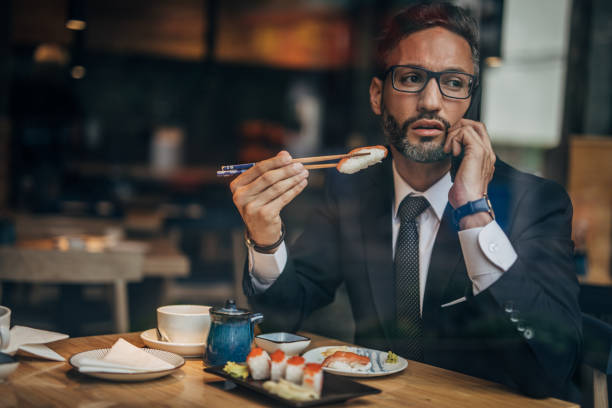 istock Man in the sushi restaurant using phone 1160821489