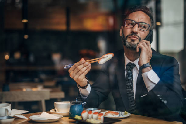 istock Man in the sushi restaurant using phone 1160821518