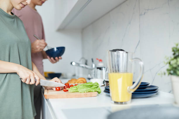 istock Young family standing by kitchen table and cooking breakfast 1160827254