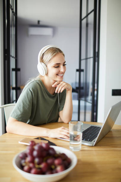 Cute cheerful woman looking at laptop display while networking