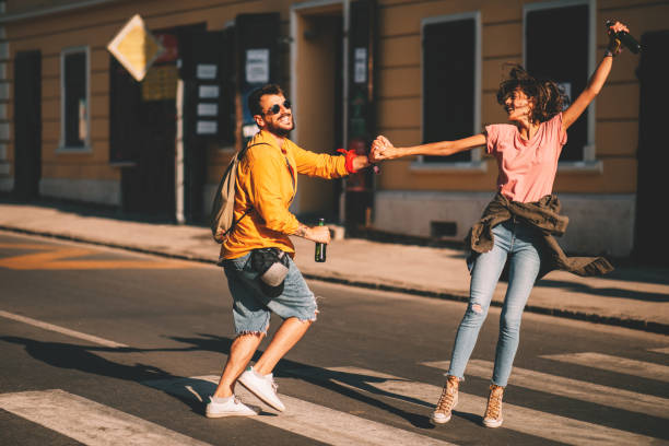 Young couple dancing on the street and holding two bottles of beer Young couple dancing on the street and holding two bottles of beer street friends stock pictures, royalty-free photos & images