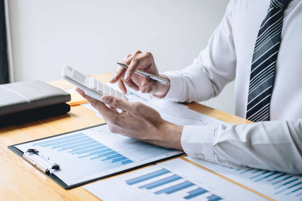 istock Businessman accountant working analyzing and calculating expense financial annual financial report balance sheet statement and analyze document graph and diagram, doing finance making notes on report 1160828497