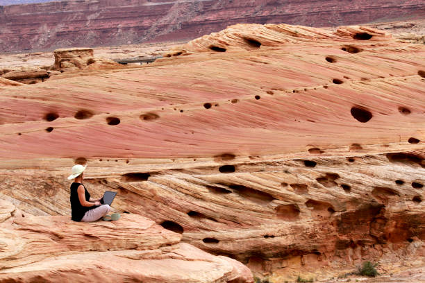 istock A woman working on laptop computer high up on rocks. 1160835637
