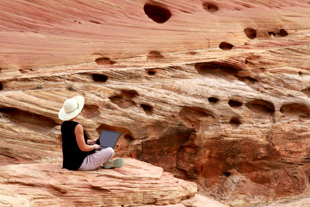istock A woman working on laptop computer high up on rocks. 1160836502