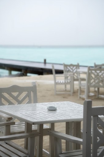 White table restaurant on the beach. The rainy season has begun.