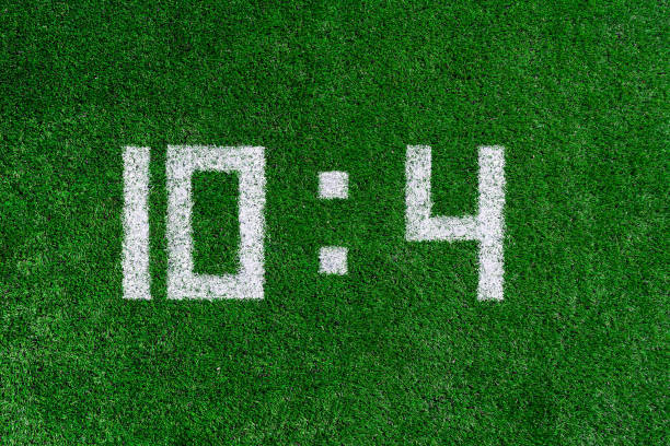 istock Football score 10:4.White numbers ten and four are drawn on the green grass,creative scoreboard 1160841542
