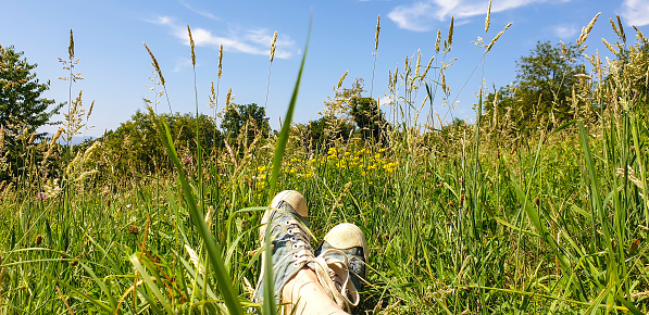 Female's feet in snickers lying in grass and flowers - personal perspective