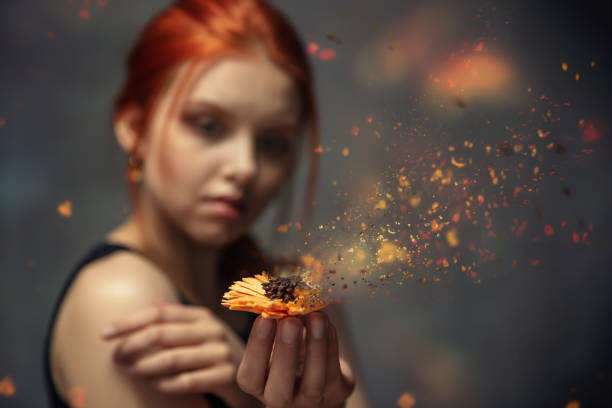 Flower crumbling in the hands of a red-haired young girl stock photo
