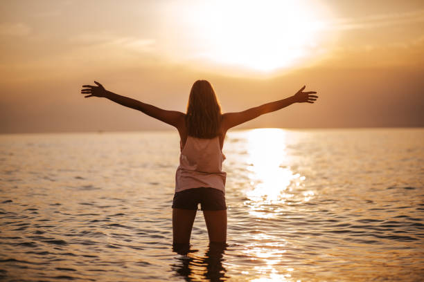 istock Young woman enjoying sunbeams during beautiful sunset 1160846650